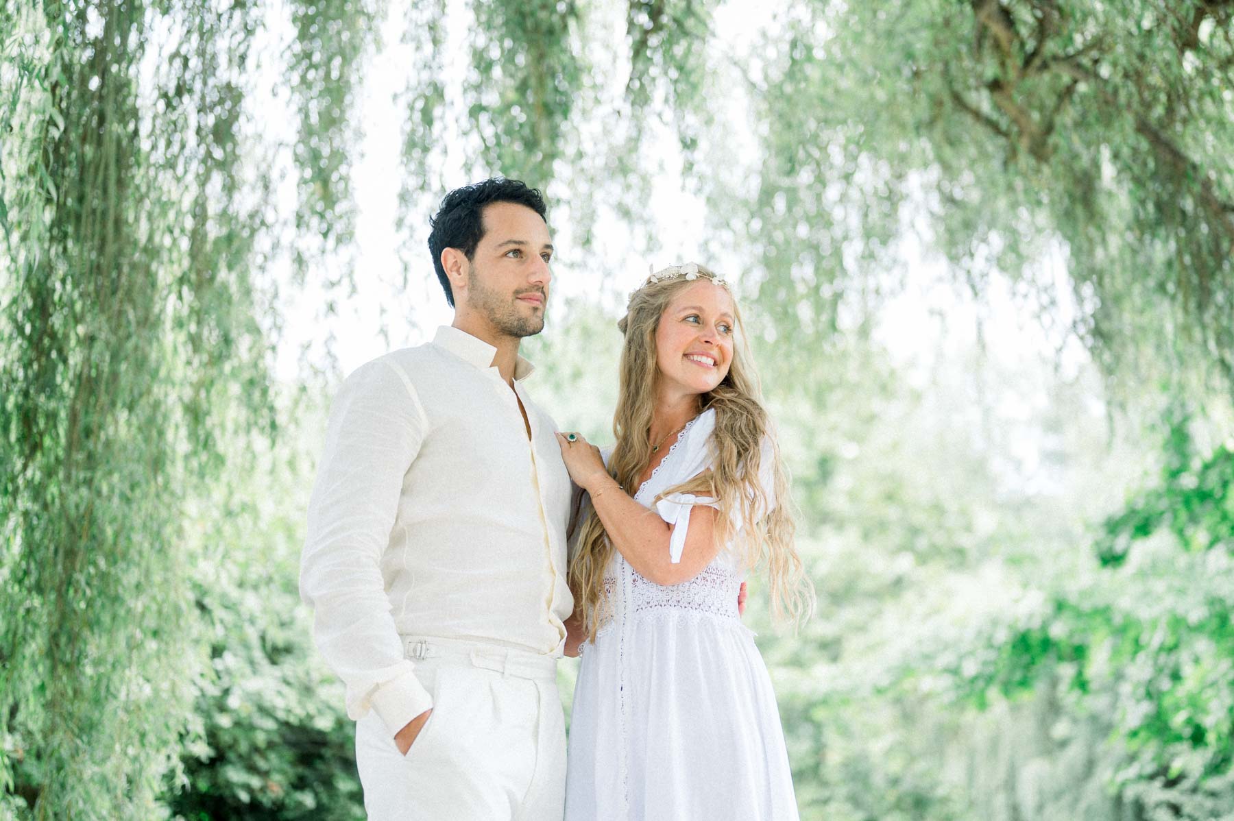 The flower-crowned bride laughing with a loved one in front of the willows