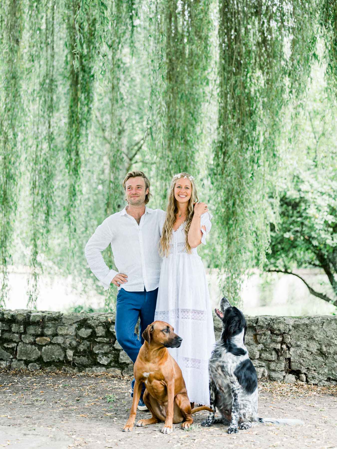 Virginie and Victor with their two dogs in front of a low stone wall
