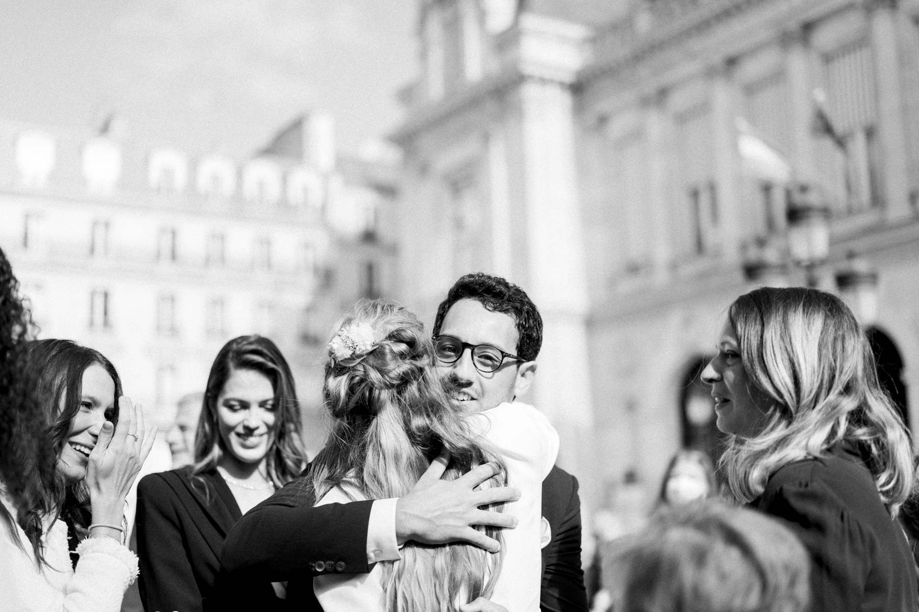 Guests hugging and greeting each other outside the town hall, in black and white