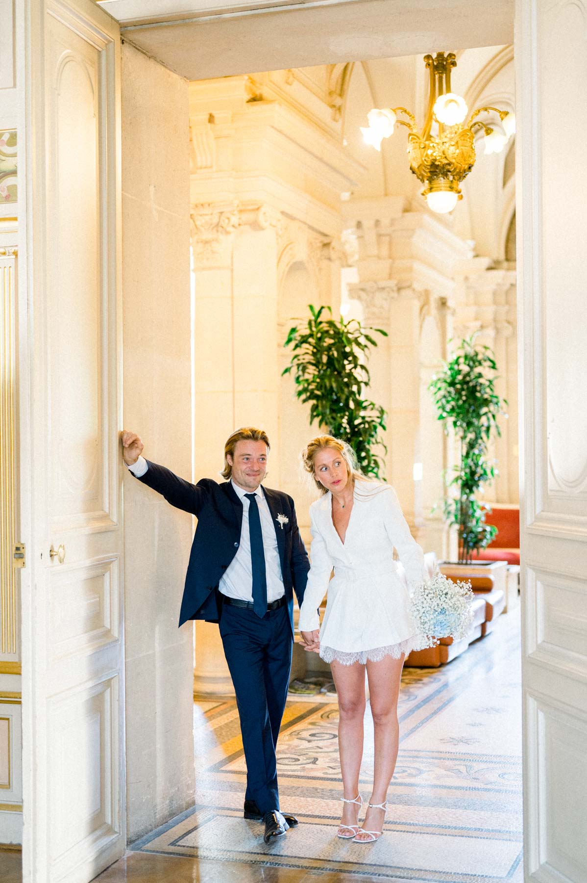 The couple walking hand in hand into the gilded hall of Neuilly town hall