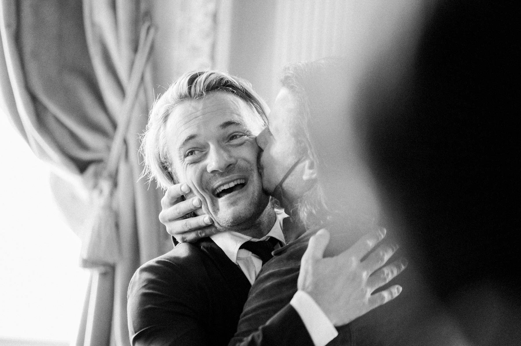 The emotional groom embracing a loved one after the ceremony, in black and white