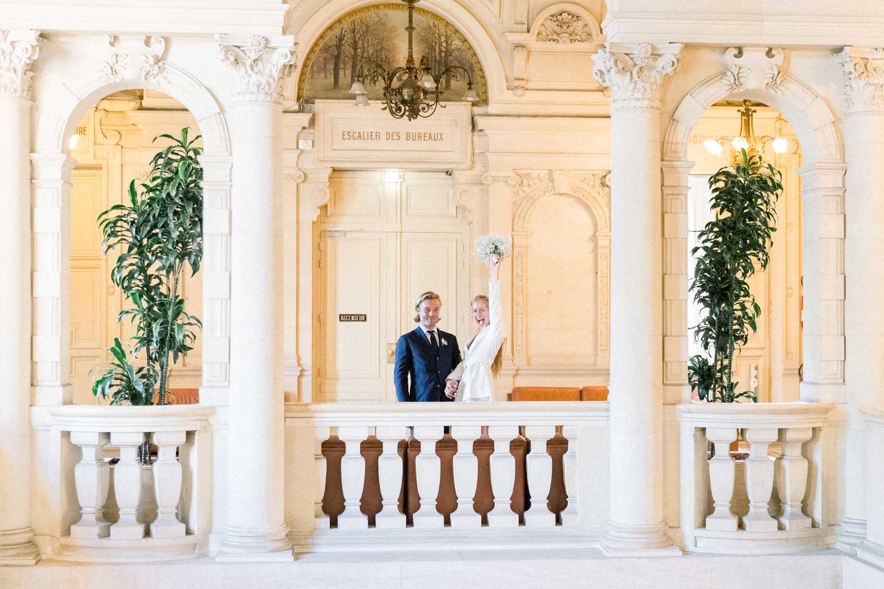The couple on the balcony between white columns and palms of the town hall