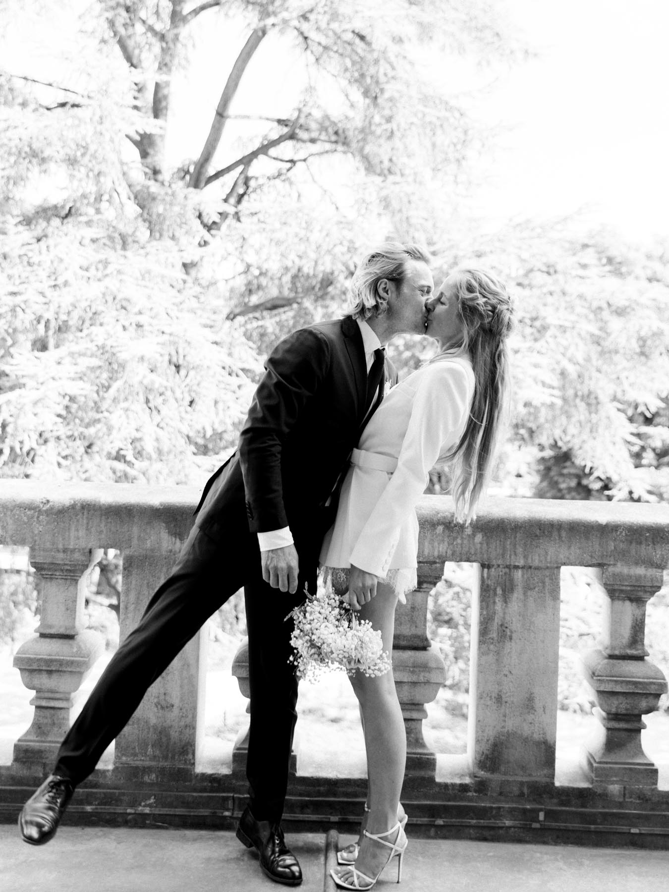 The groom dips the bride for a kiss by the town hall balustrade, in black and white
