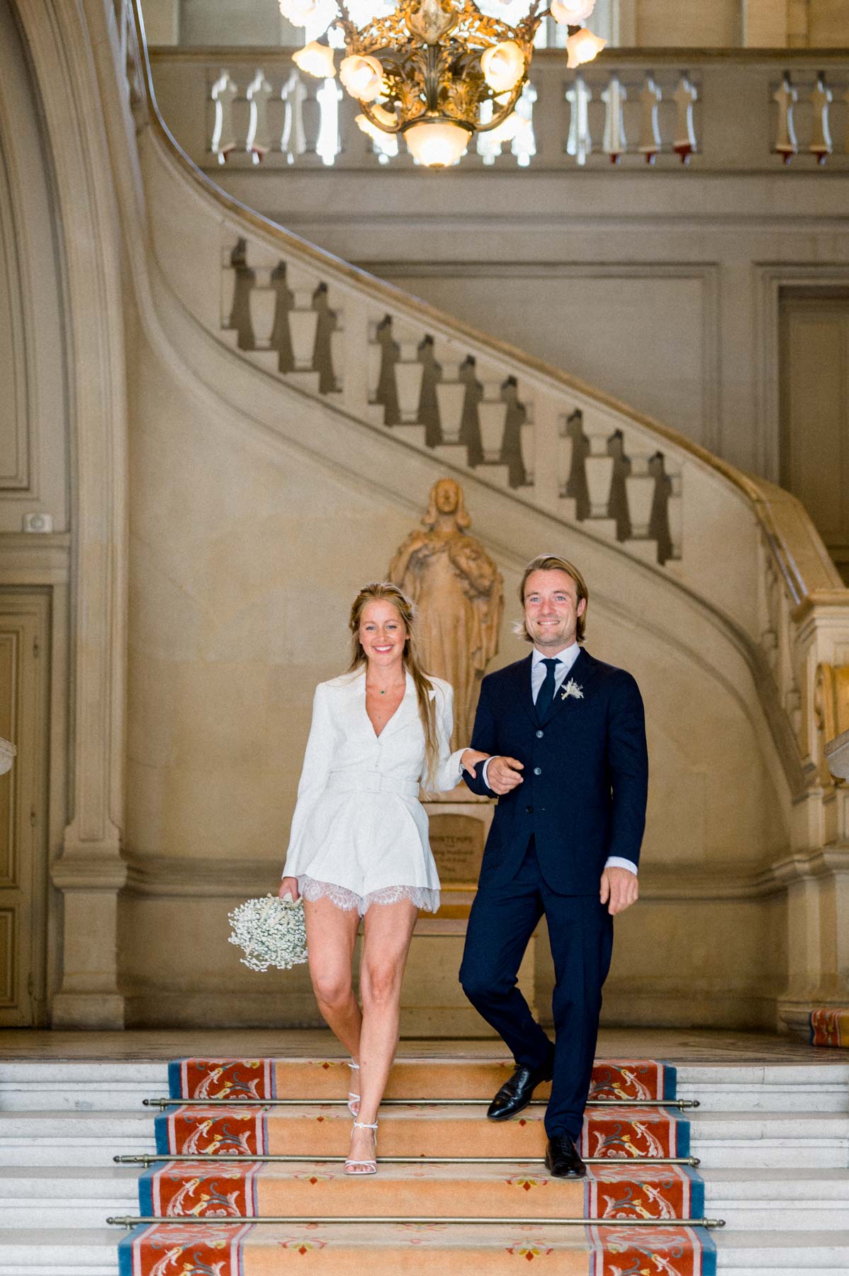 The couple descending the red-carpeted grand staircase of Neuilly-sur-Seine town hall