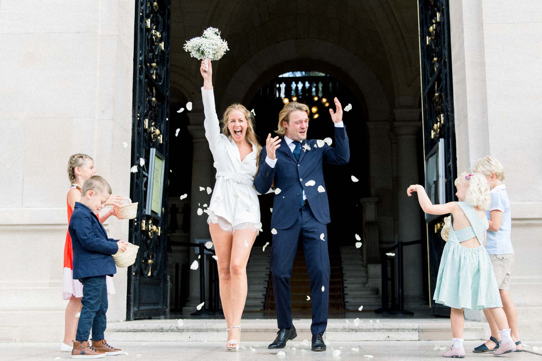 The couple stepping out under petals thrown by children at Neuilly town hall