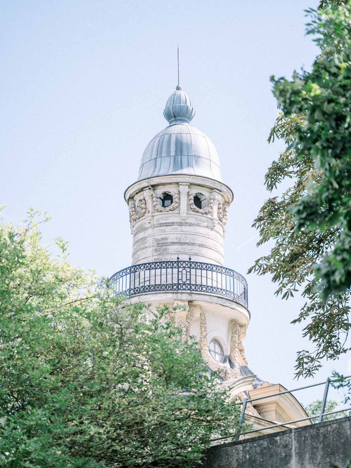 Domed tower rising above the trees under a blue sky near the Camping de Paris
