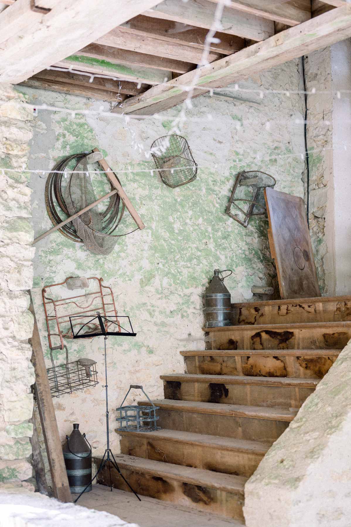 Wooden staircase and old tools hanging in a stone barn at Moulin de Launoy