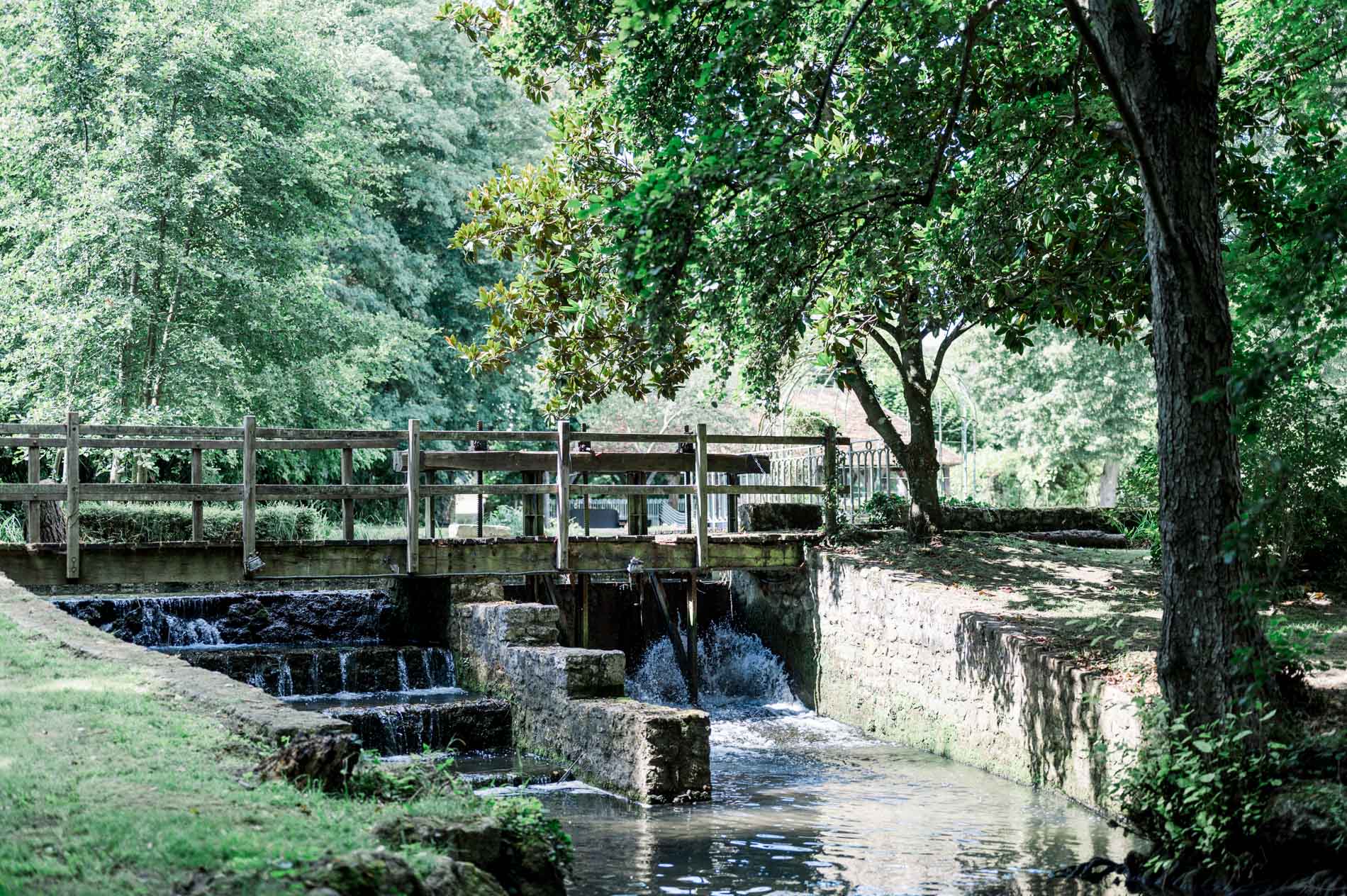 Wooden footbridge and small cascades on the river at Moulin de Launoy