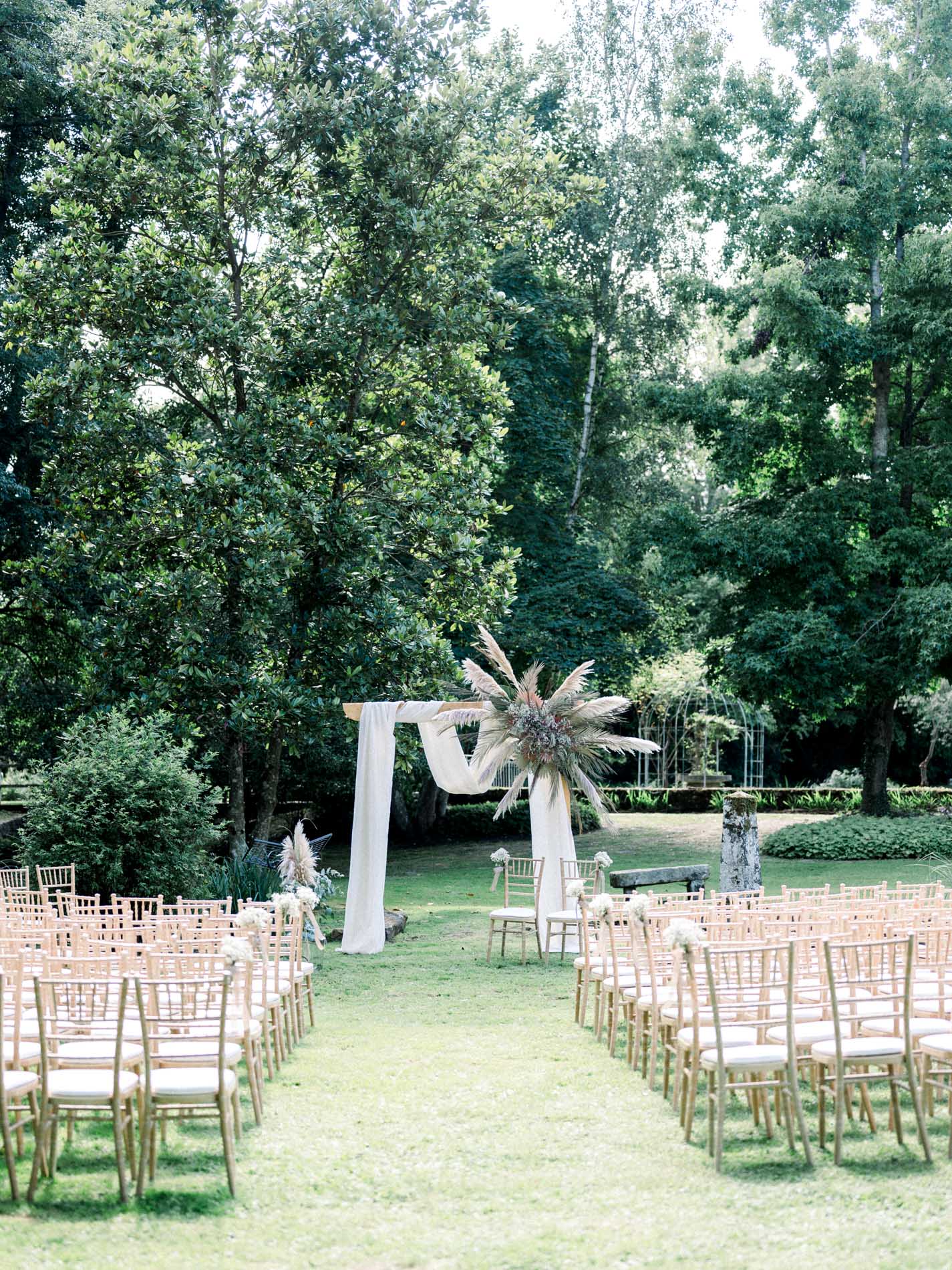 White-draped arch and rows of chairs for the outdoor ceremony at Moulin de Launoy
