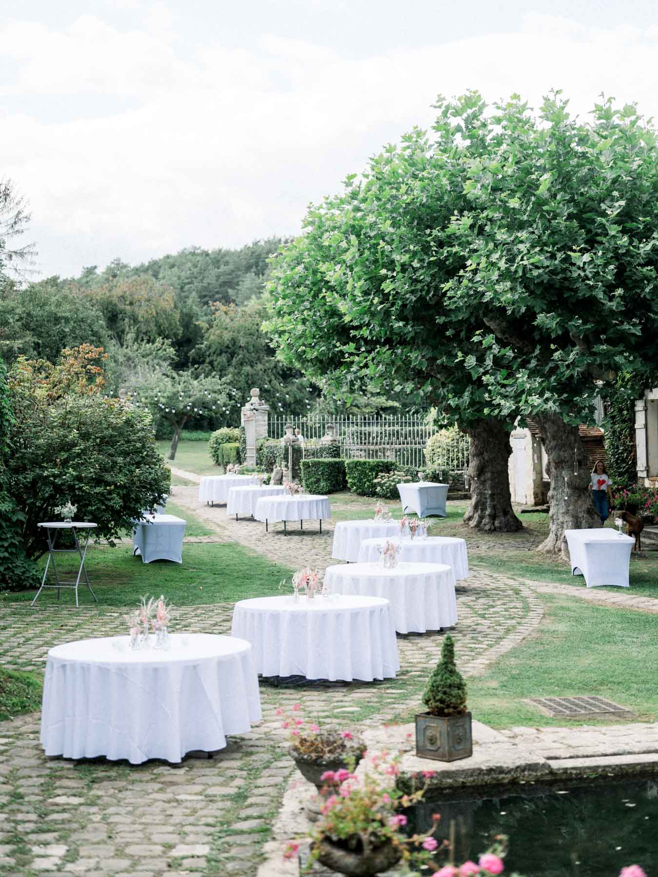 White-draped cocktail tables in the garden for the reception at Moulin de Launoy