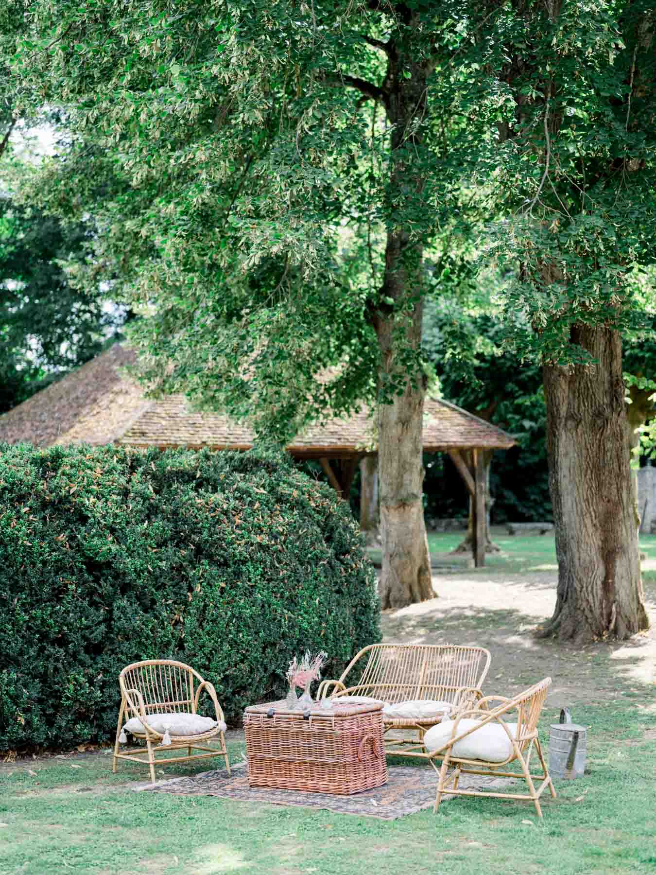 Rattan garden lounge set up beneath tall trees for the drinks reception