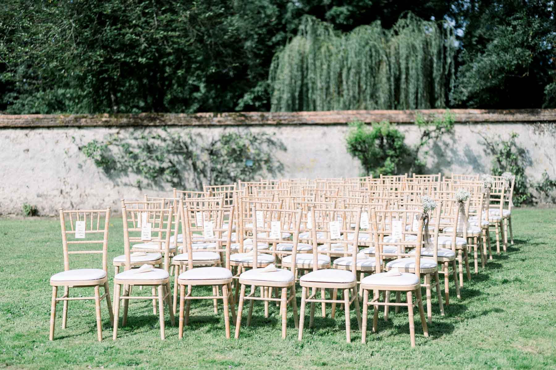 Rows of wooden chairs before a stone wall for the outdoor ceremony