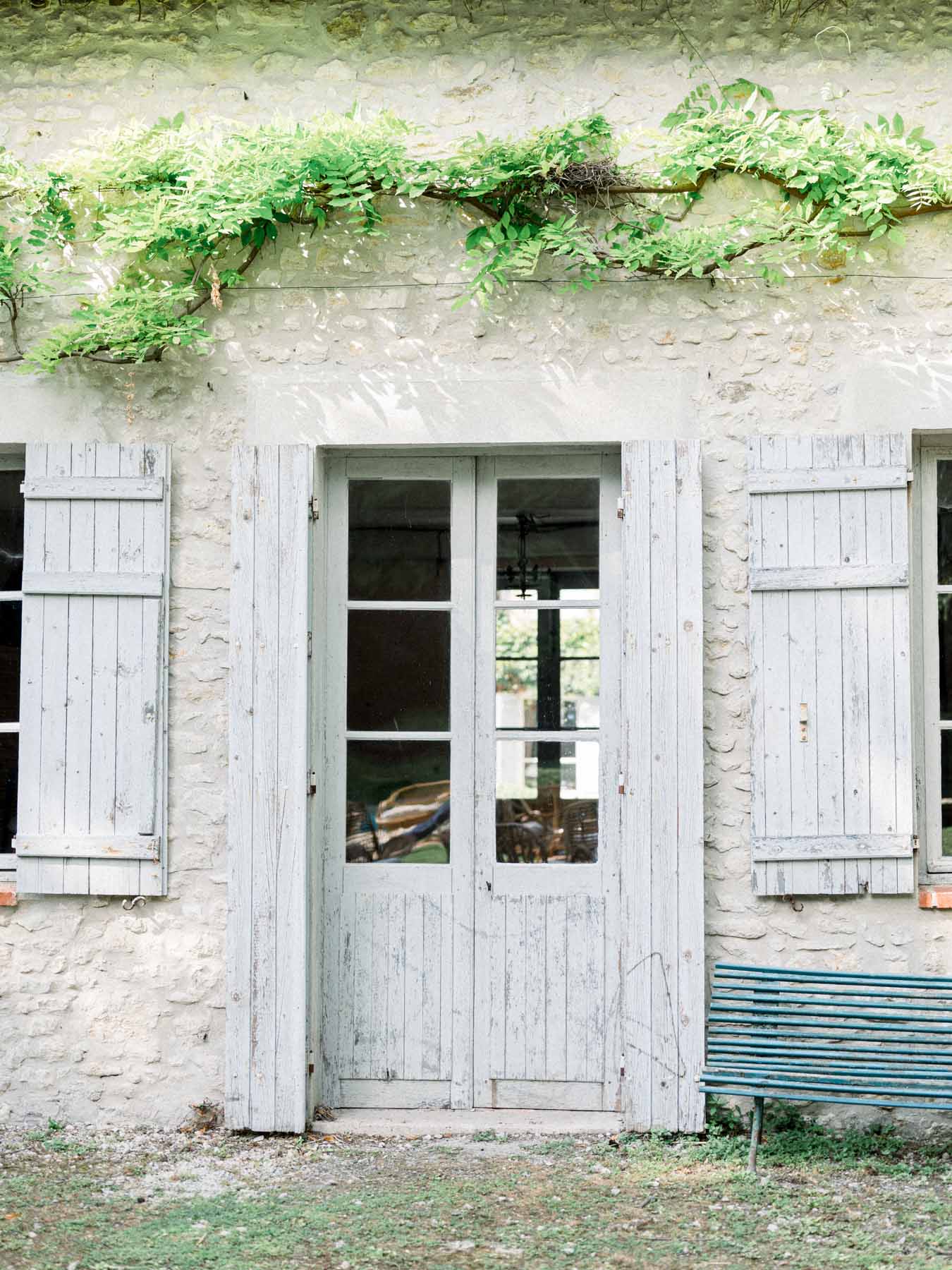 Weathered white door and shutters on a stone façade at Moulin de Launoy
