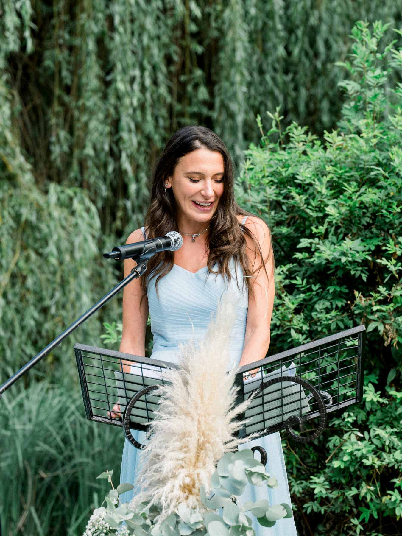 A guest reading a speech at the microphone during the outdoor ceremony