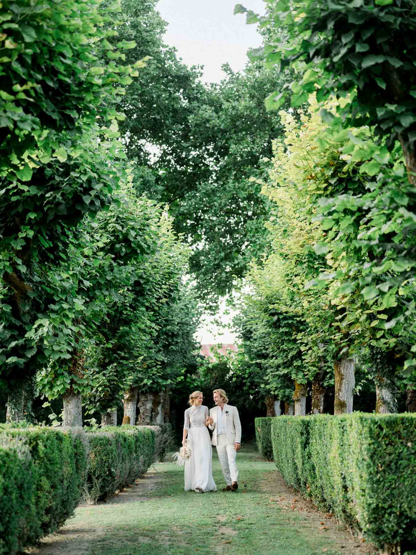 The couple at the end of an avenue of clipped hedges and tall trees