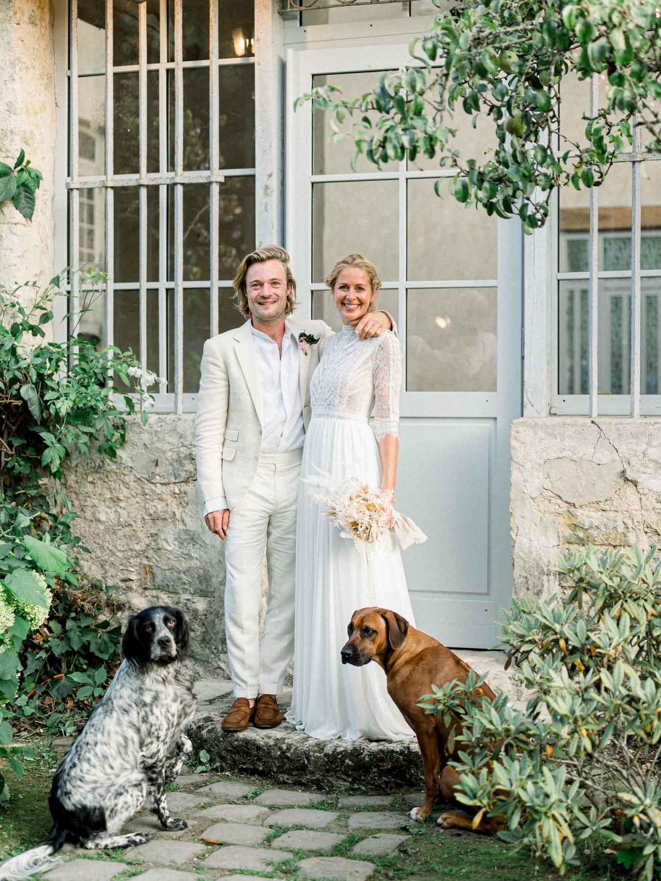 The couple in front of the house door with their two dogs