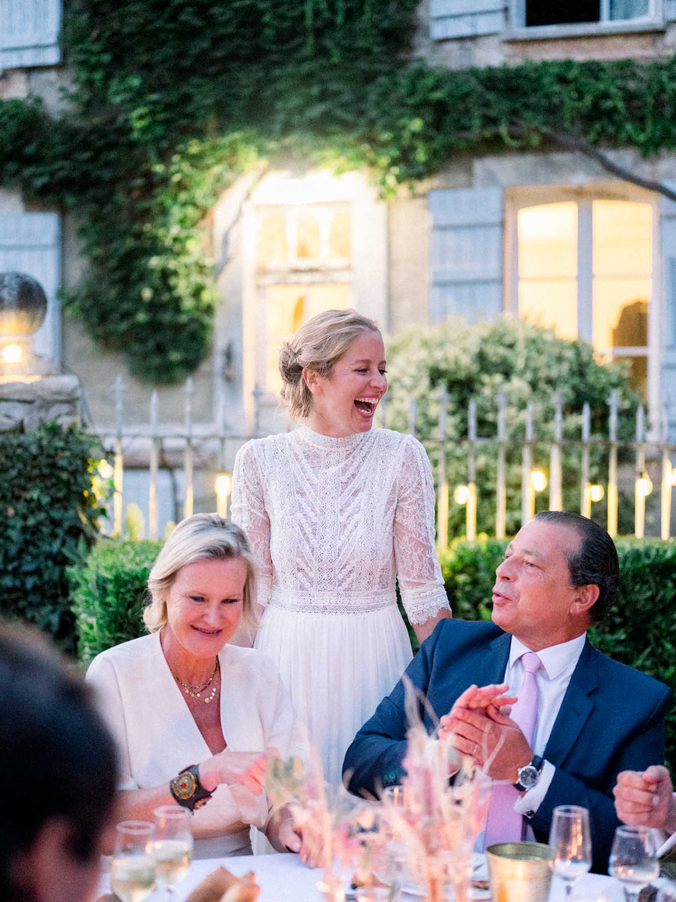 The bride bursting into laughter at the dinner table among guests