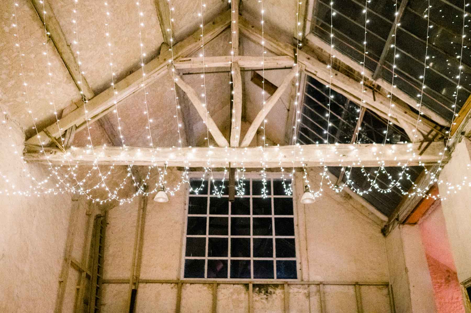 Timber roof beams of the barn lit with fairy lights