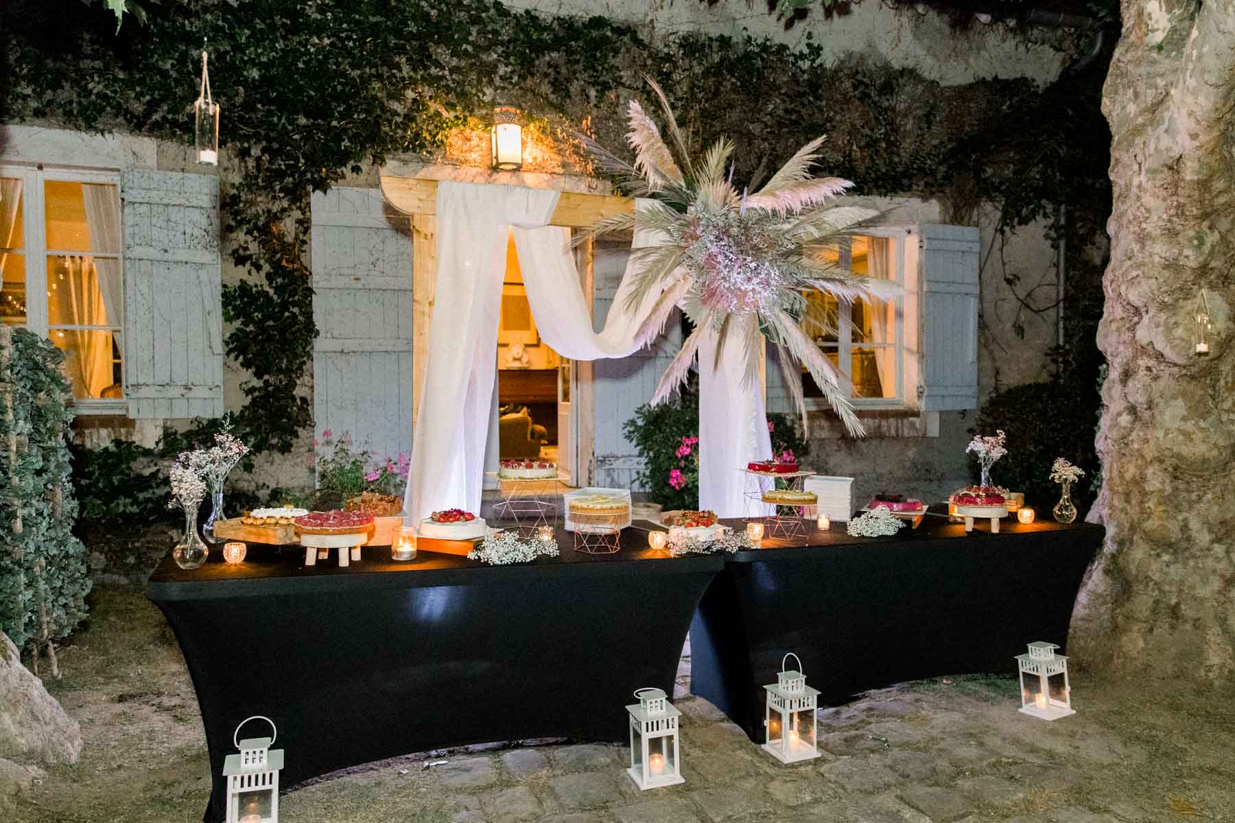 Dessert table before a window draped with fabric and dried flowers