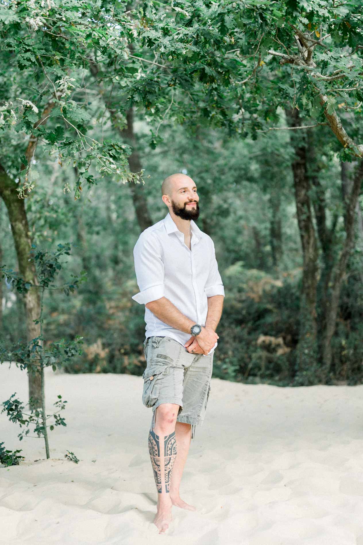 Man in a white shirt walking barefoot on the sandy forest floor
