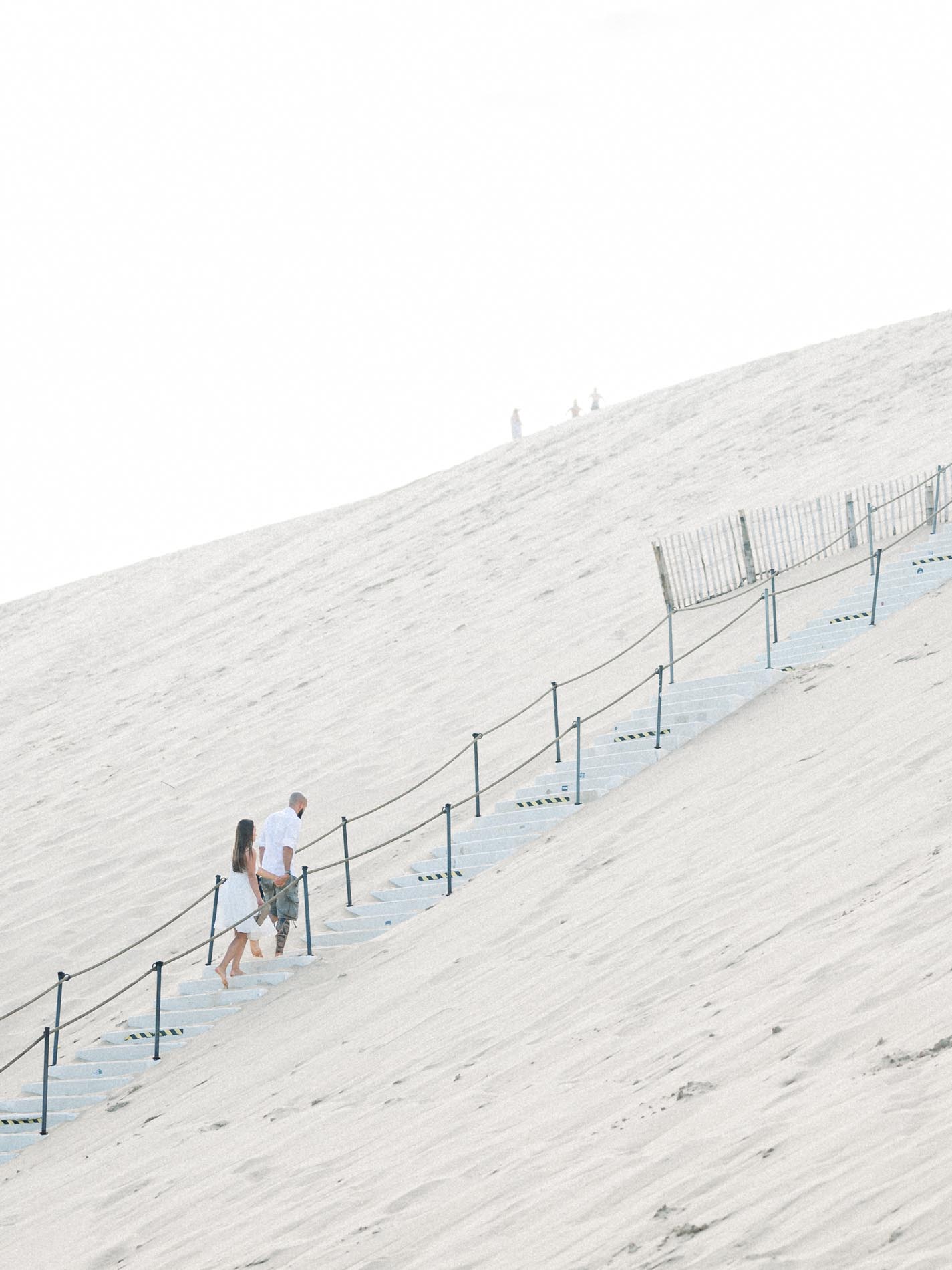 Couple climbing the Dune du Pilat stairway hand in hand