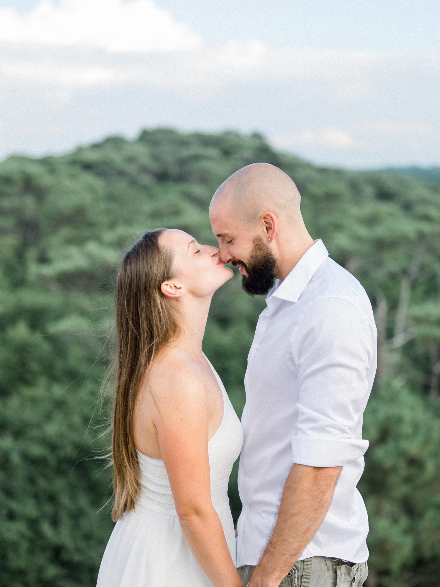 Couple about to kiss on top of the dune with the forest behind