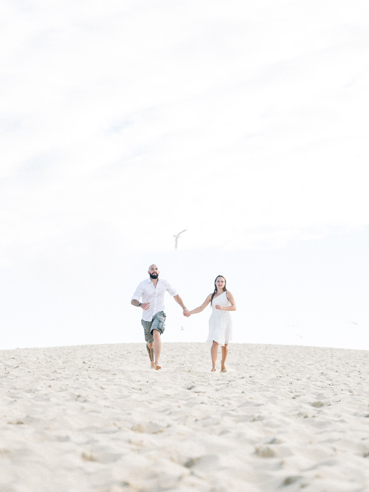 Couple walking hand in hand along the sandy crest of the dune
