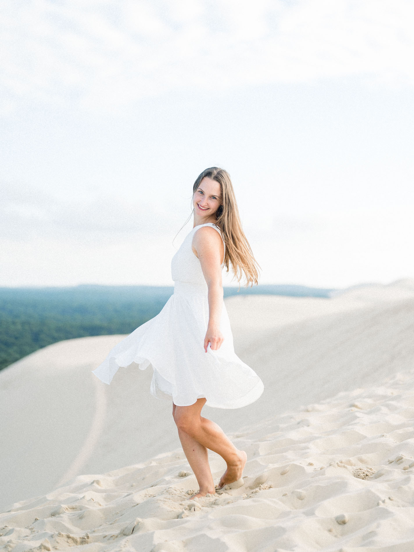 Young woman twirling her white dress on the Dune du Pilat
