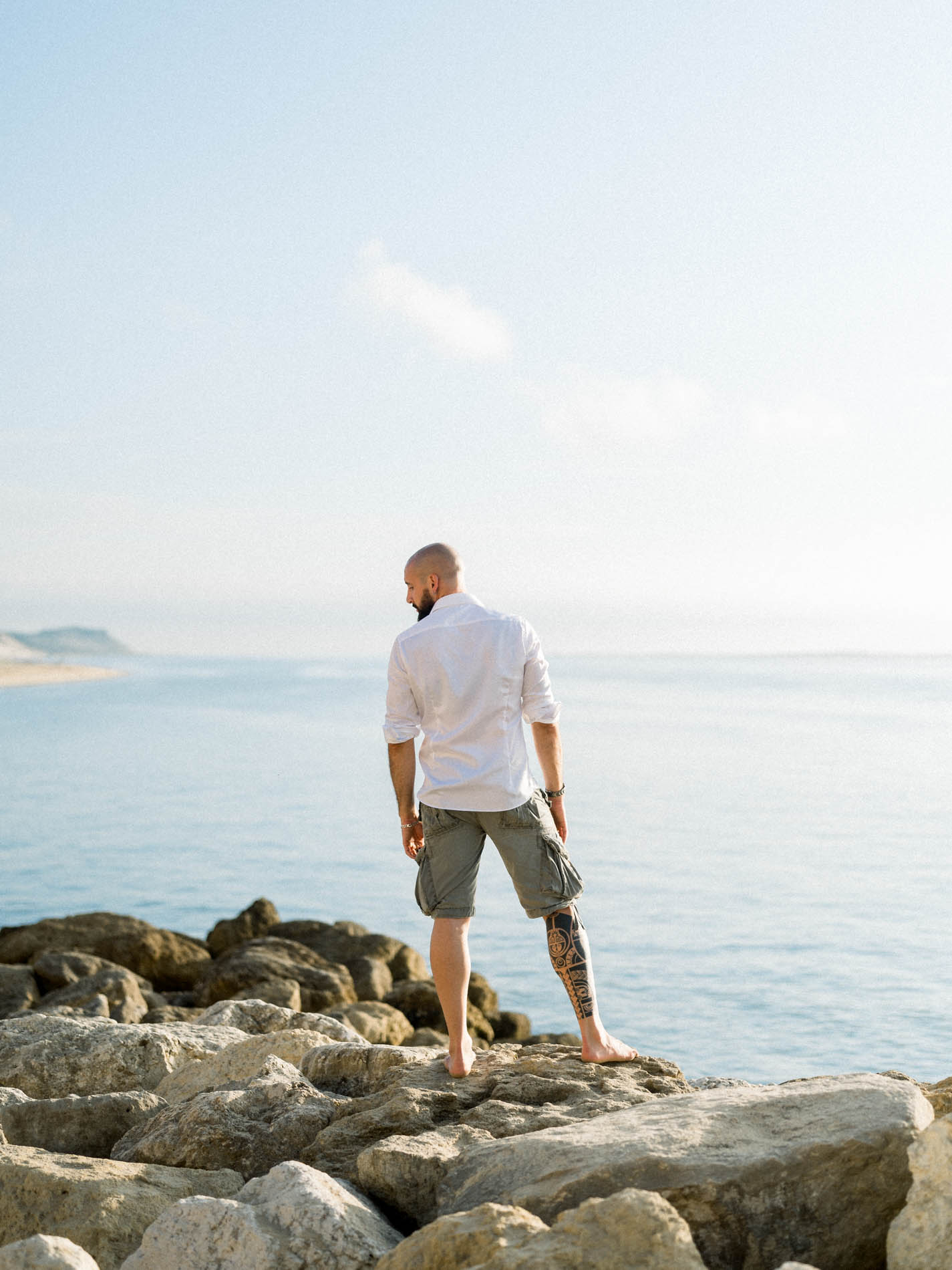 Man in a white shirt standing on rocks facing the Arcachon Bay