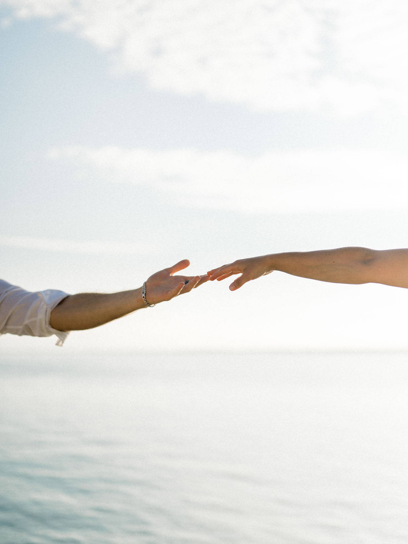 The couple's hands about to touch above the water