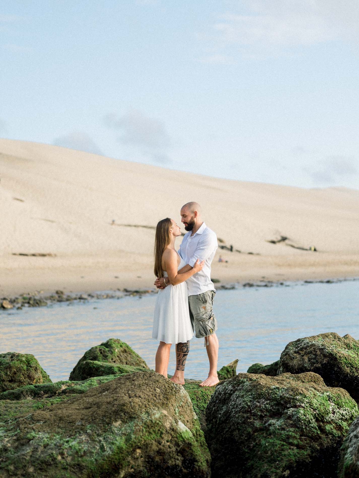 Couple embracing on the rocks with the Dune du Pilat behind them