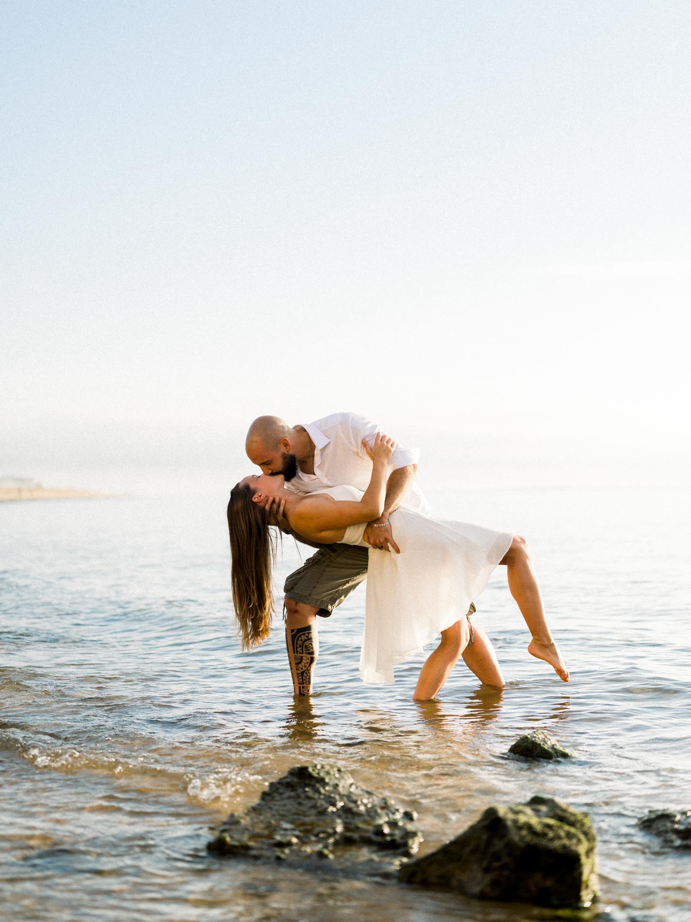 Couple kissing in the water among the rocks at the foot of the dune