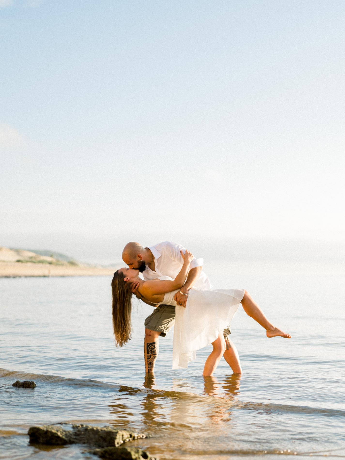 Man dipping his partner for a kiss in the shallow water