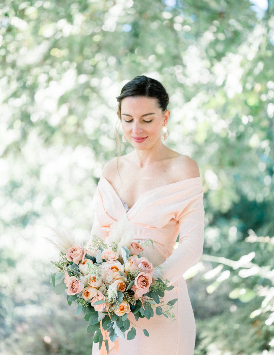 Young woman smiling in an off-the-shoulder dress with a pastel bouquet