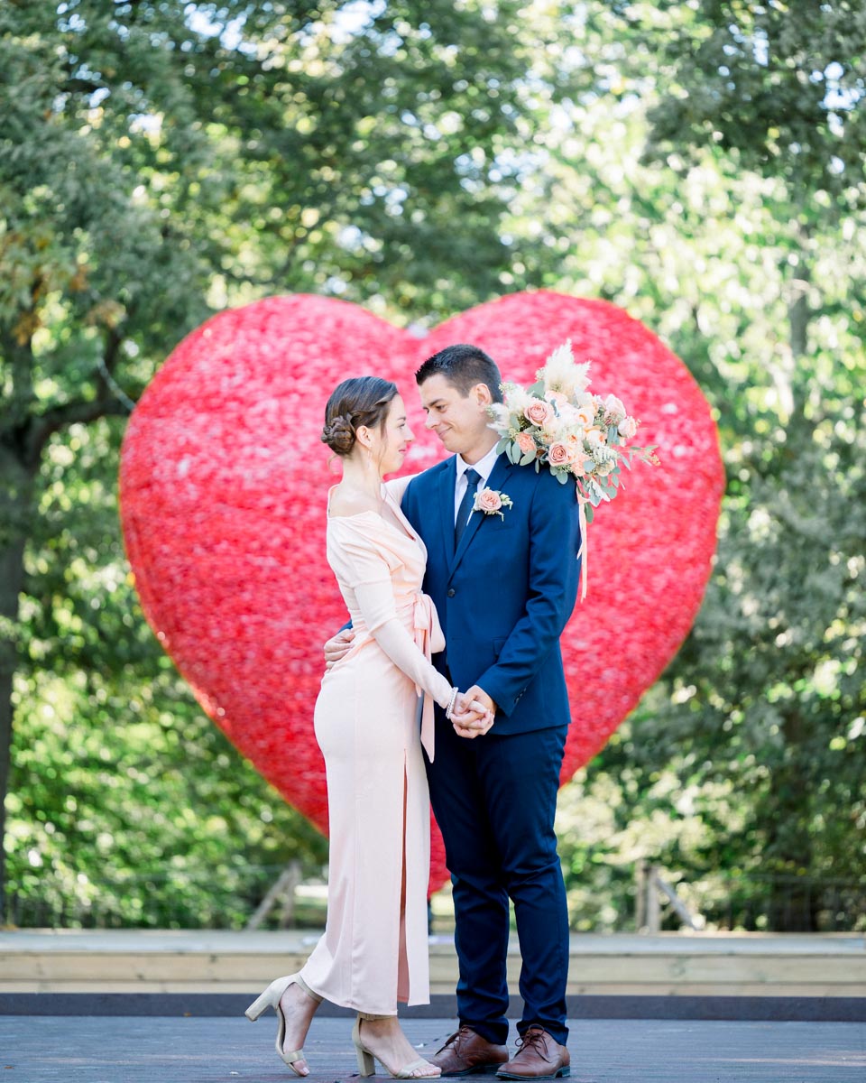 The newly PACSed couple holding hands in front of a large red heart