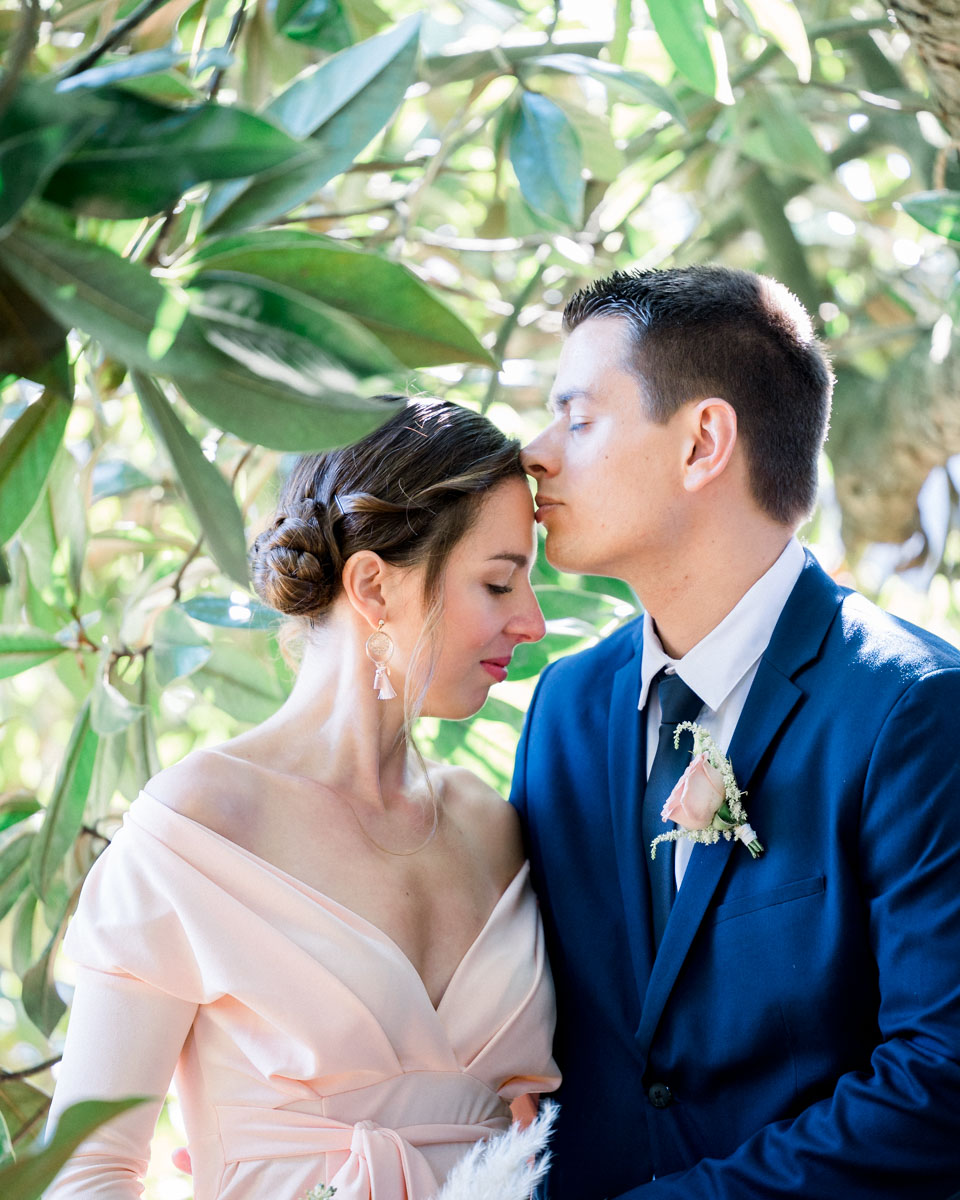 He kisses his partner's forehead beneath the foliage