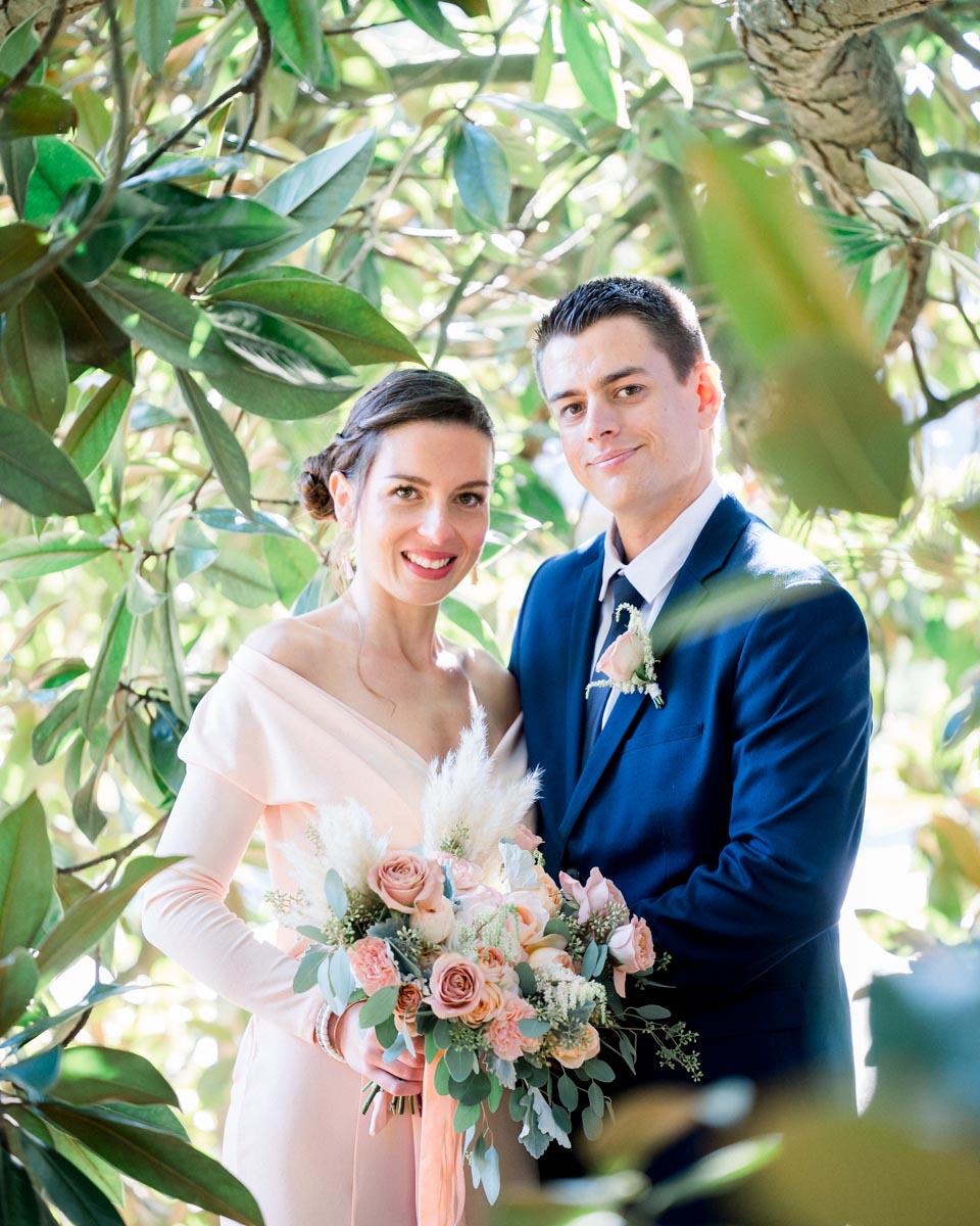 The smiling couple posing together among the glossy magnolia leaves