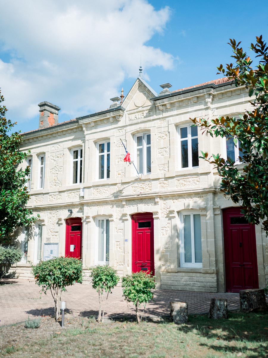 Balizac town hall façade with red doors under a summer sky