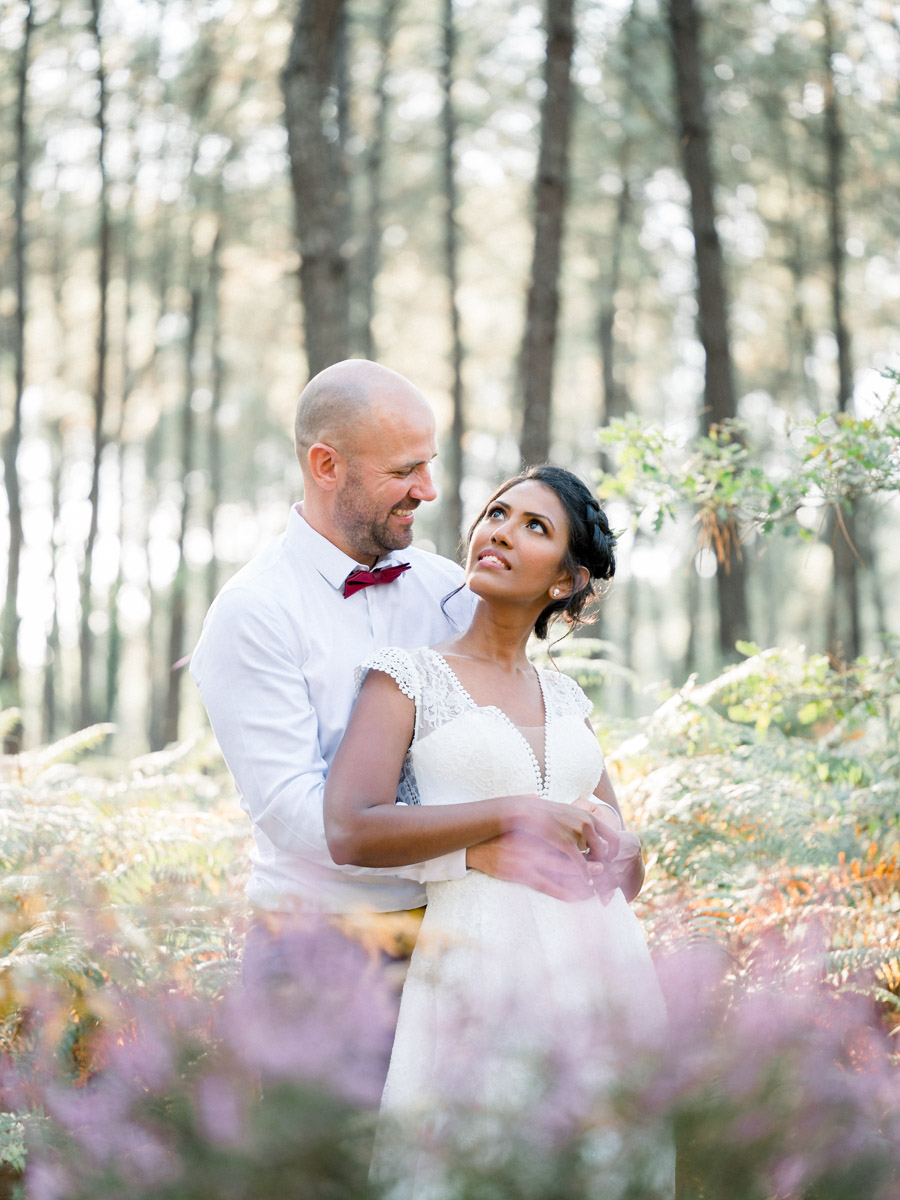 The groom embracing the bride from behind amid flowering heather
