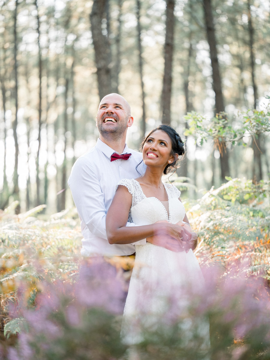 The couple gazing into the distance, embracing among pines and mauve heather