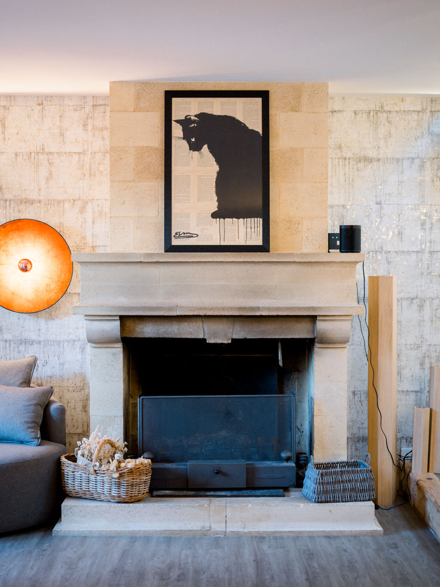 Stone fireplace and black cat poster in the lounge of Le Résinier, Le Barp