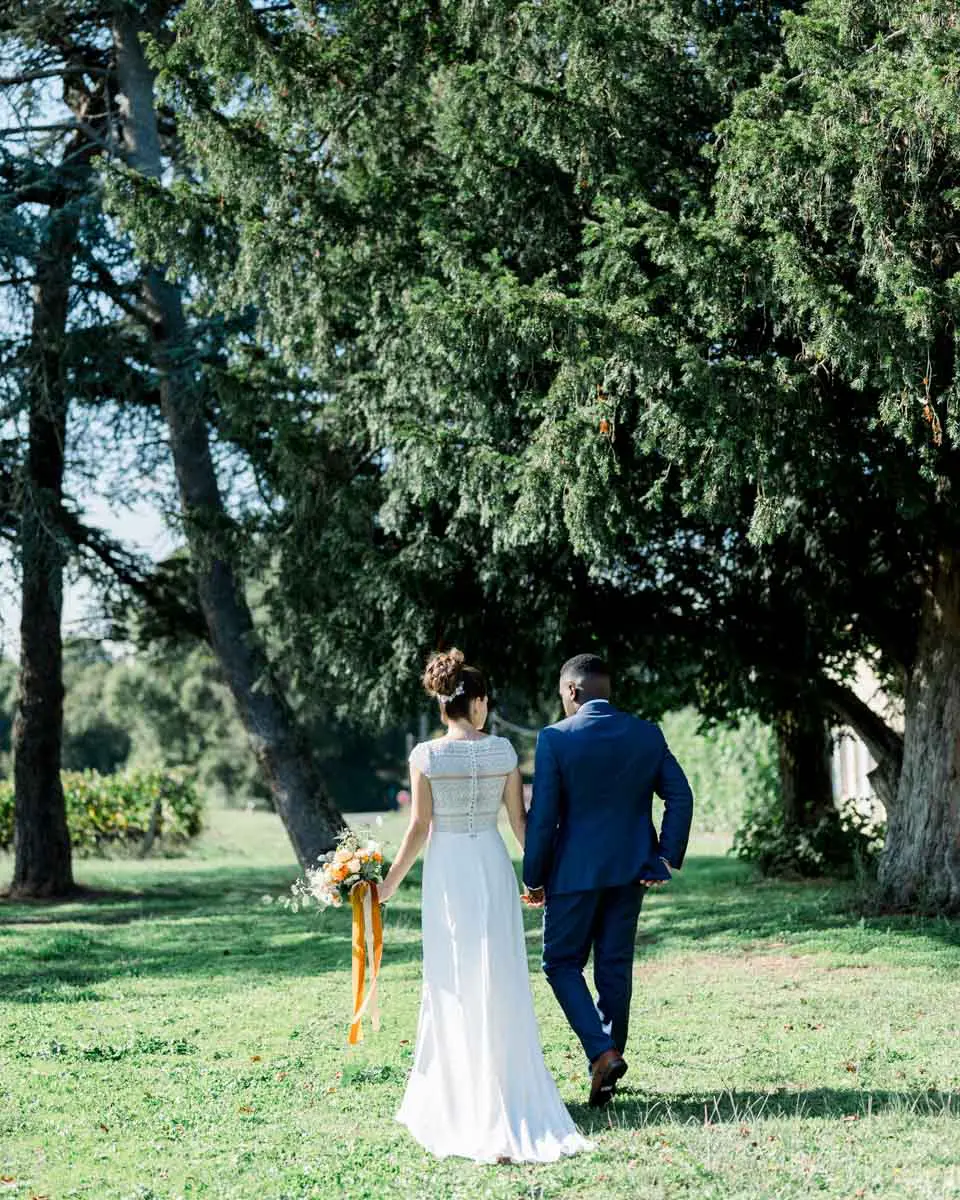 The couple seen from behind walking under the tall trees of the park