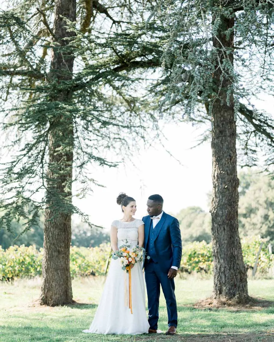 The bride and groom between two tall pines with vines behind them