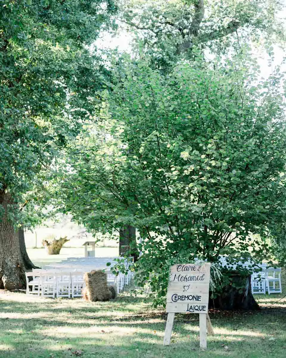 Outdoor ceremony area under the trees with a welcome sign