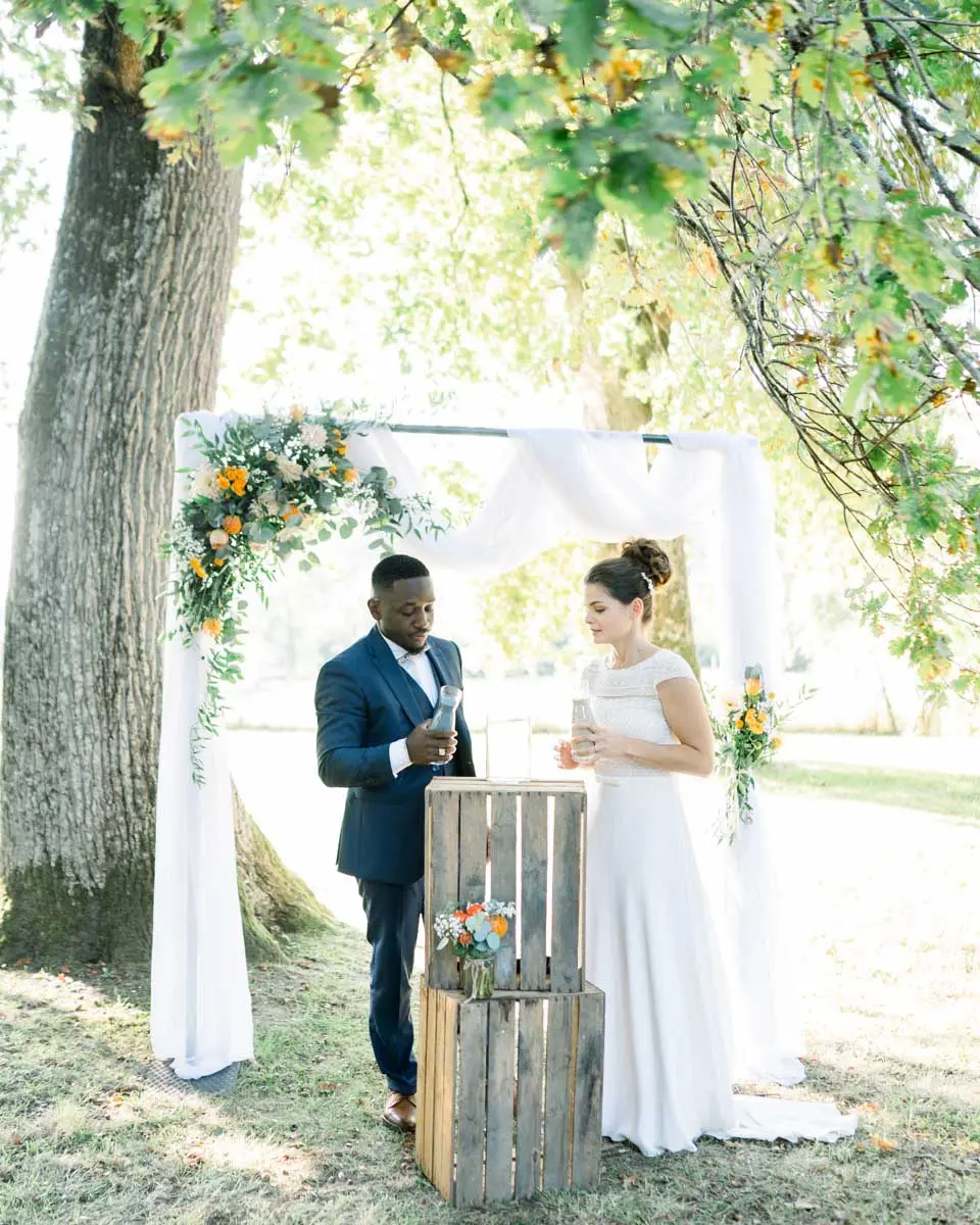 The couple under the floral arch during the outdoor ceremony at Château Courtade-Dubuc