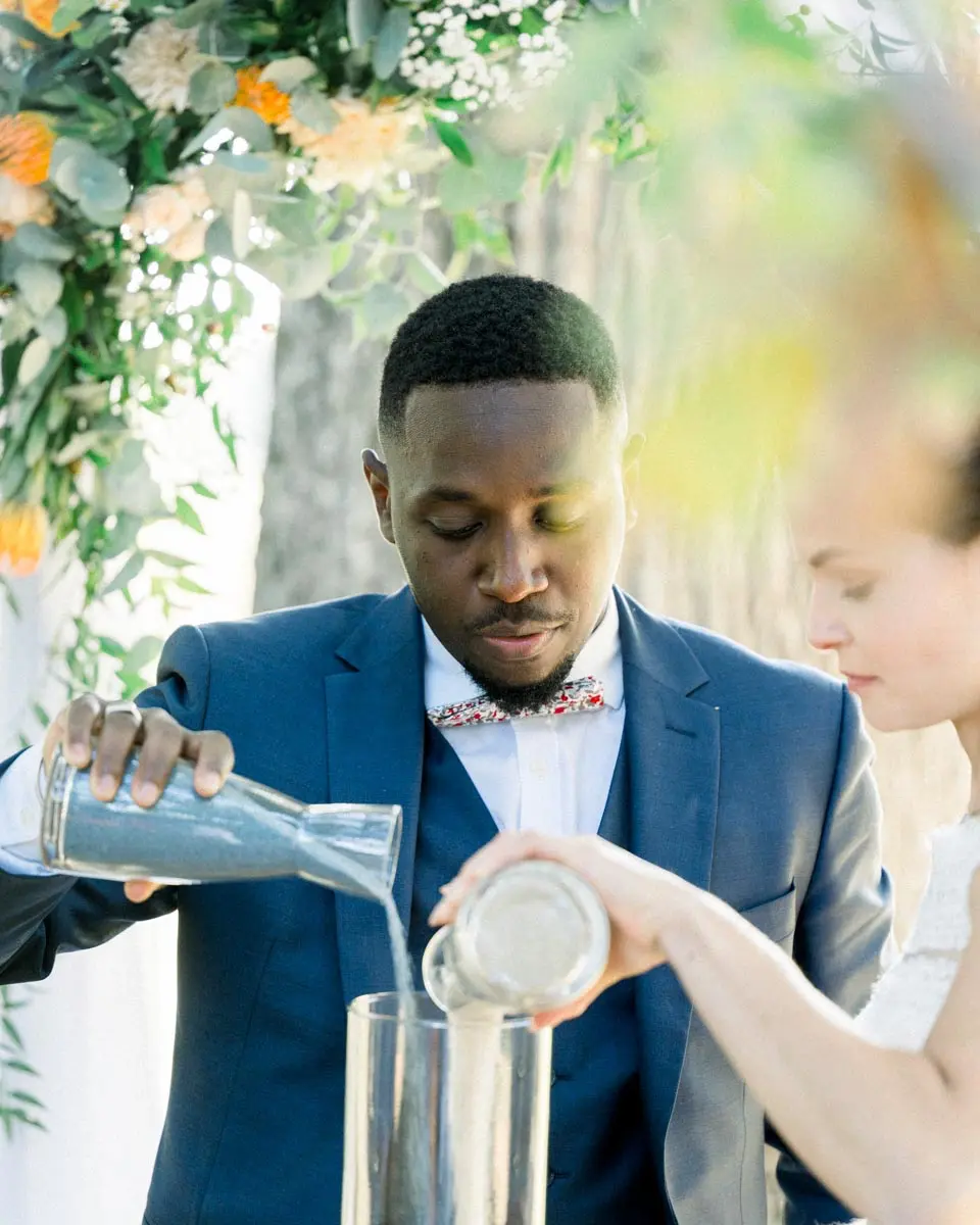 The couple pouring coloured sand into a vase during the ceremony