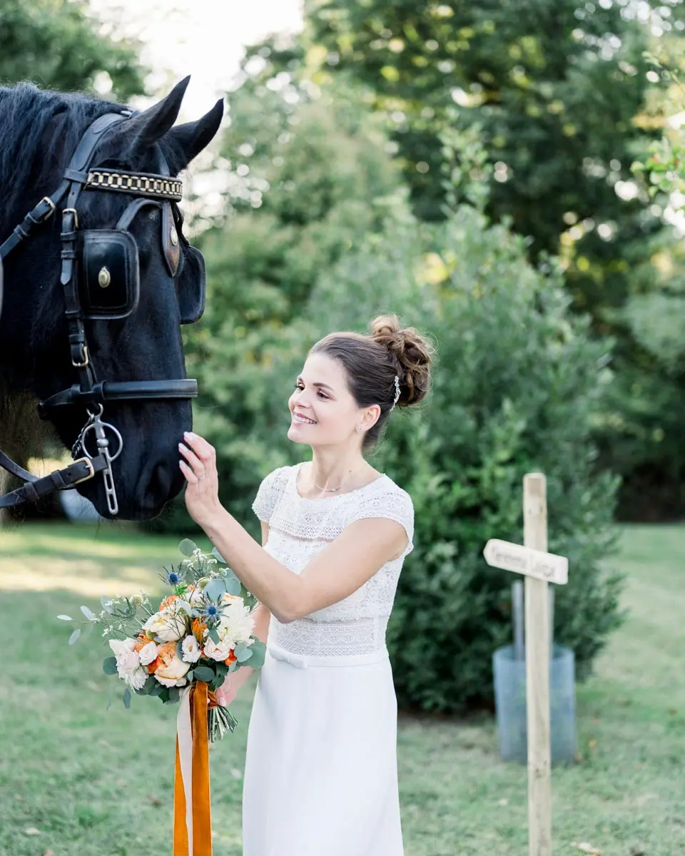 The bride stroking one of the carriage's black horses