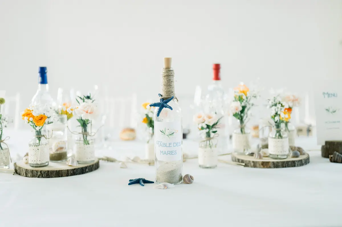 Centrepieces of orange flowers and glass bottles on wooden log slices