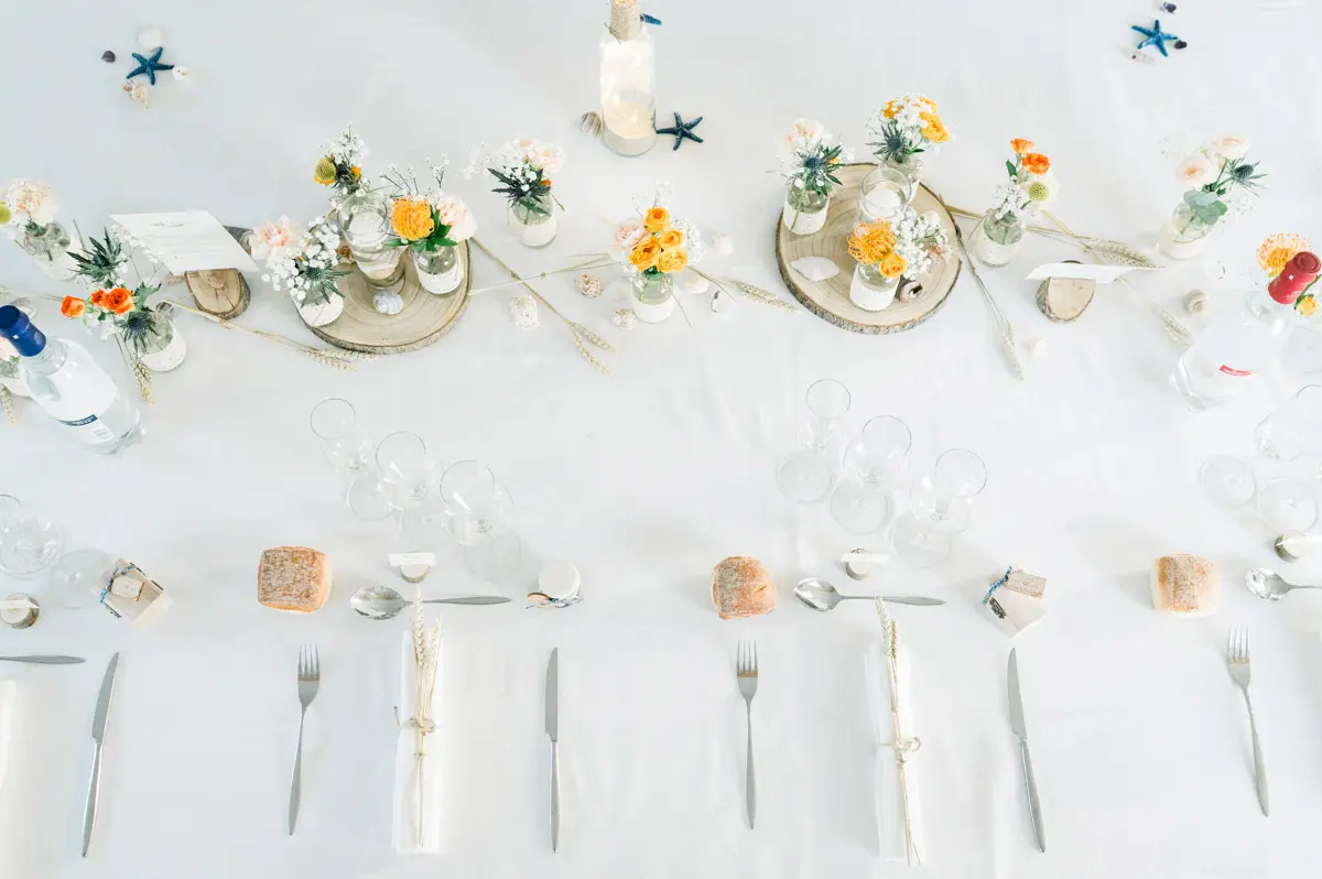 Overhead view of a wedding table laid in white, orange and blue