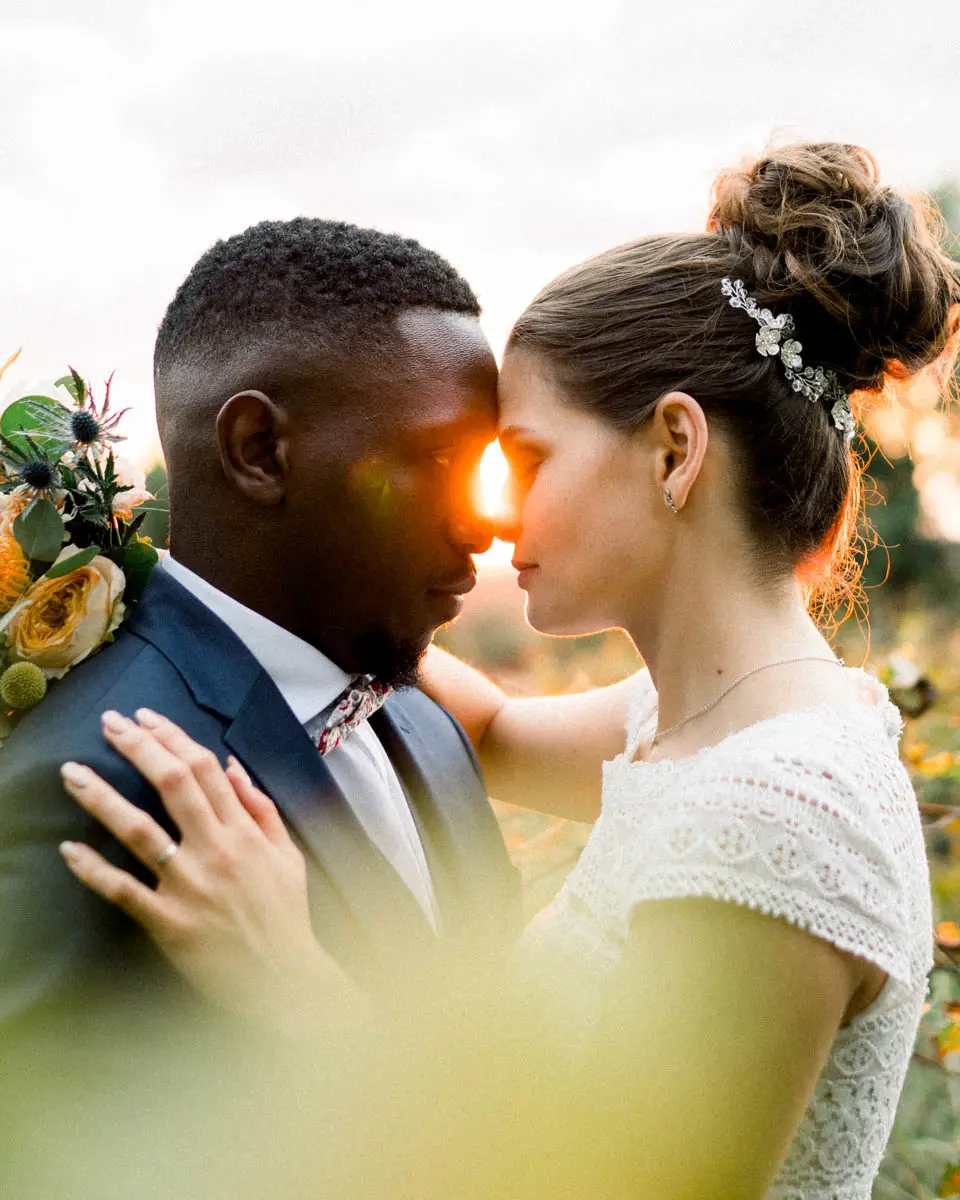 Claire and Mohamed forehead to forehead with a ray of sunlight between them